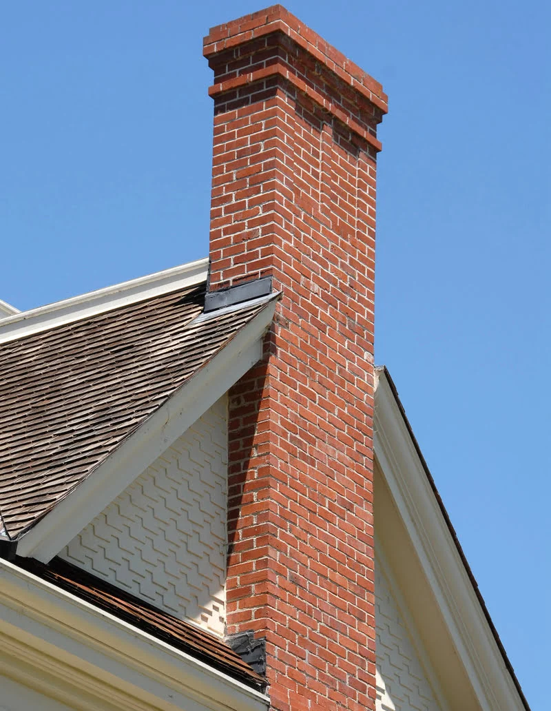 Brick chimney extending high over beautiful roof